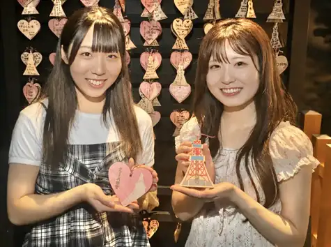 ハート型と東京タワー型の絵馬を手に持って微笑む2人の女性