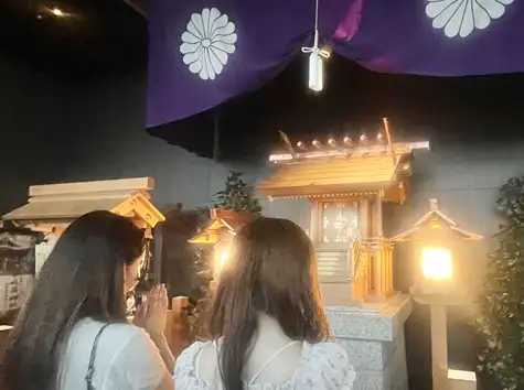 タワー大神宮の社殿の前で手を合わせてお参りする2人の女性の後ろ姿