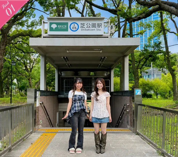 都営三田線「芝公園駅」の出入口前で笑顔で並んで立つ2人の女性