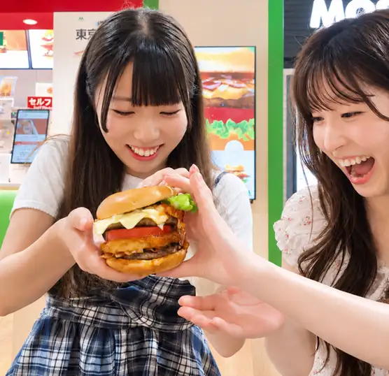 店舗限定の「東京タワーバーガー」を手に笑顔を見せる2人の女性