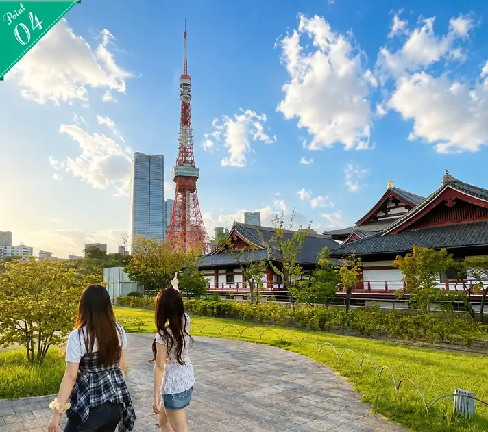 増上寺の伝統的な建物と東京タワーを眺めながら歩く後ろ姿の2人の女性